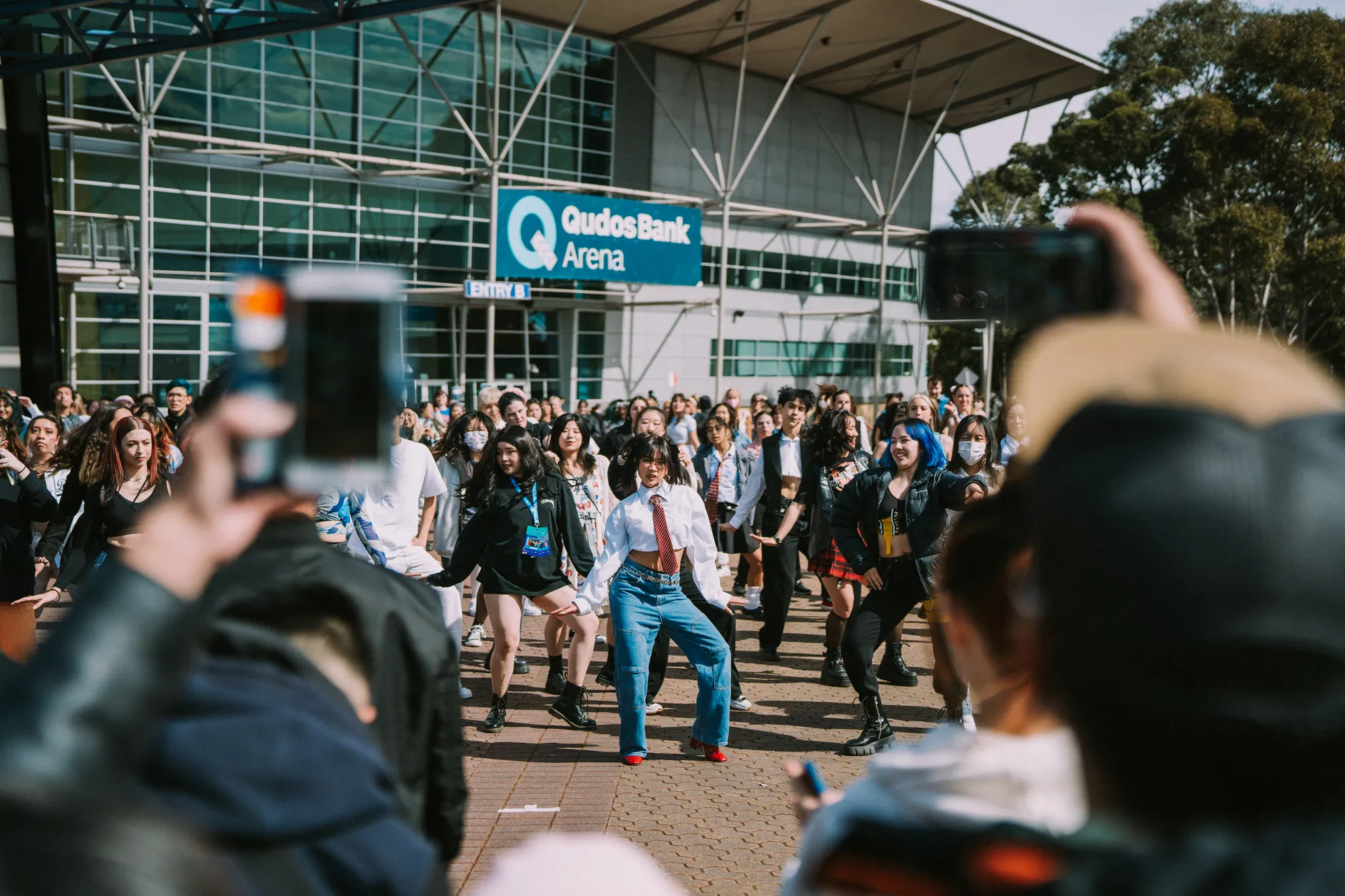 Sydney event photography: Choreographed dance flash mob outside Qudos Bank Arena with a crowd watching.