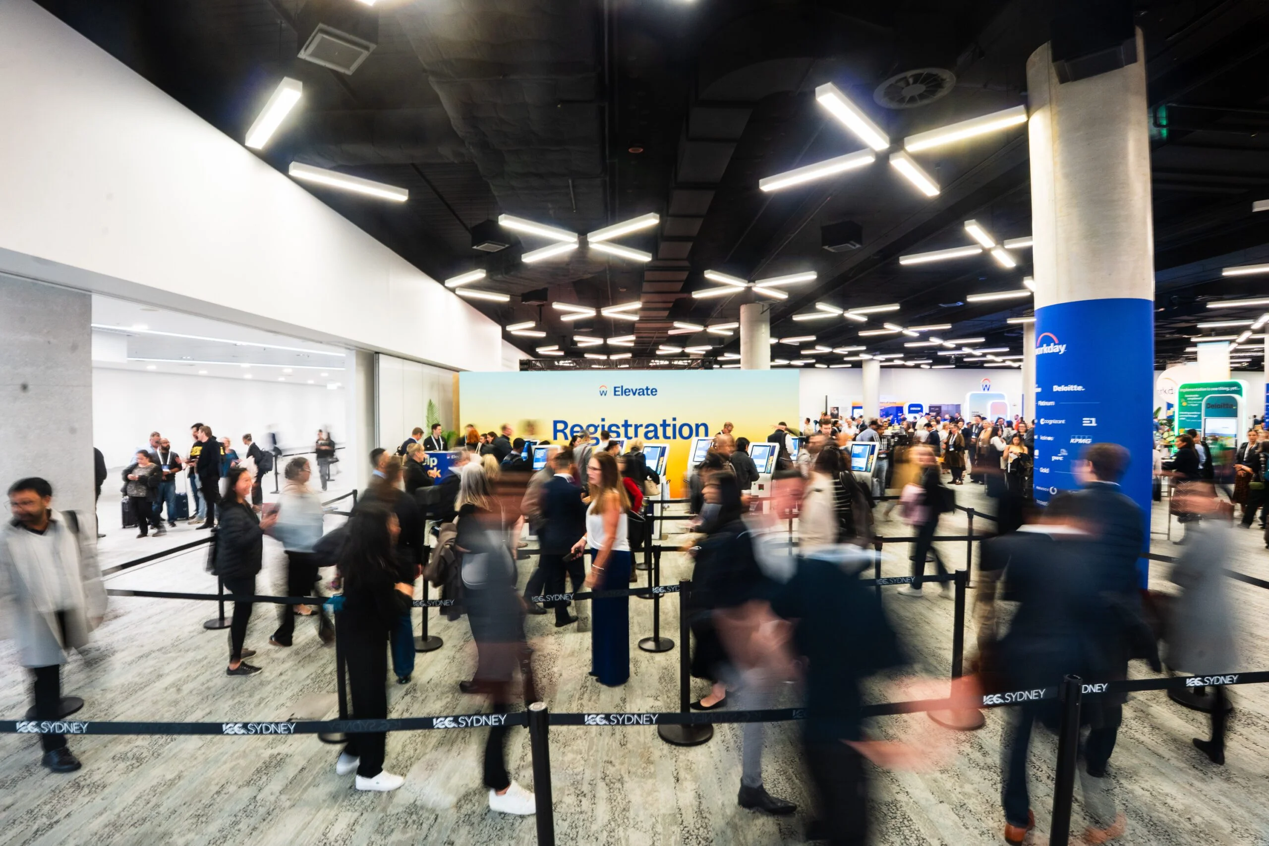 A busy conference registration and check-in area with attendees queuing at ICC Sydney.
