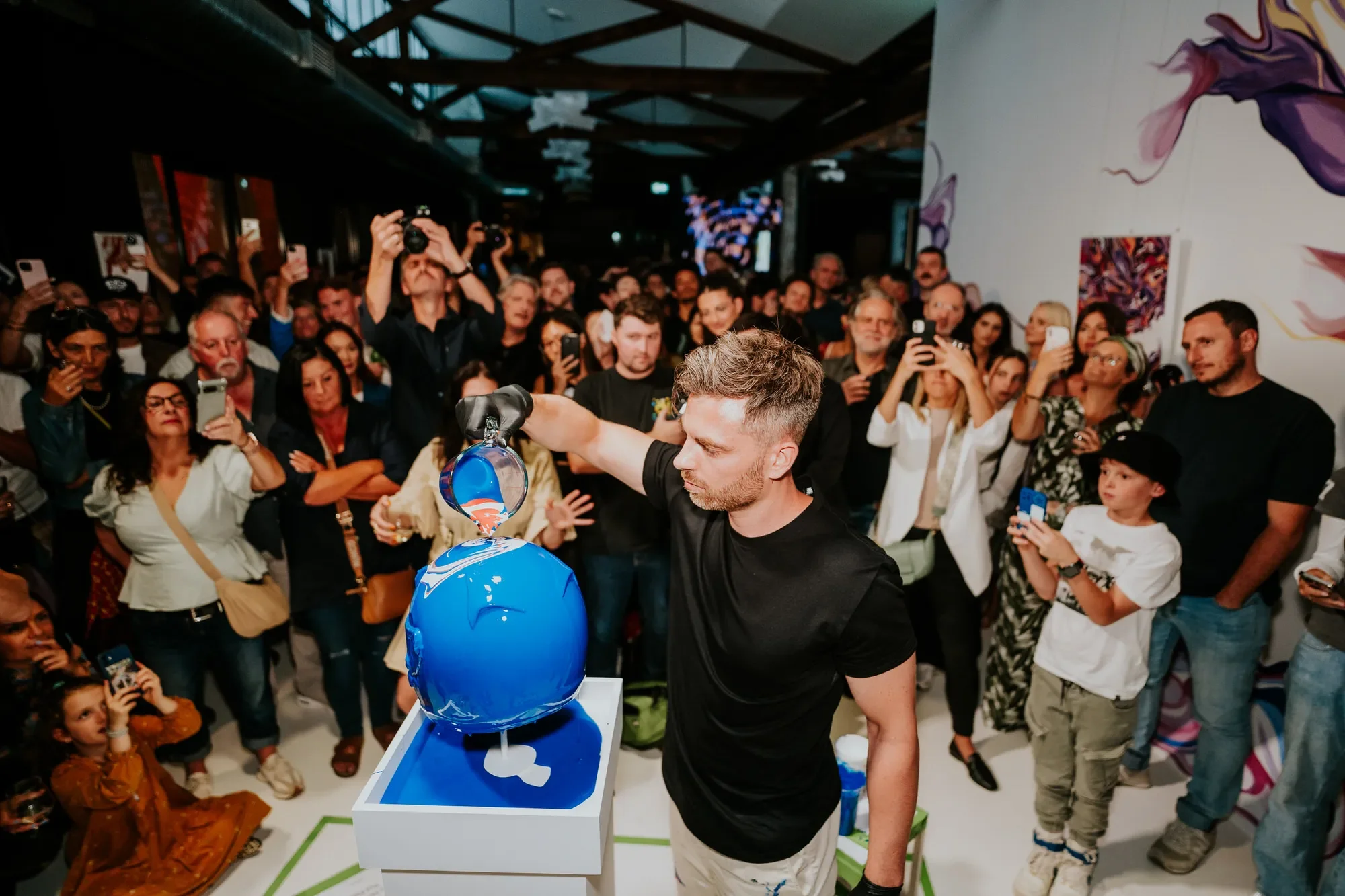 Sydney brand activation photography: Artist pouring blue paint on a head sculpture before a live audience.