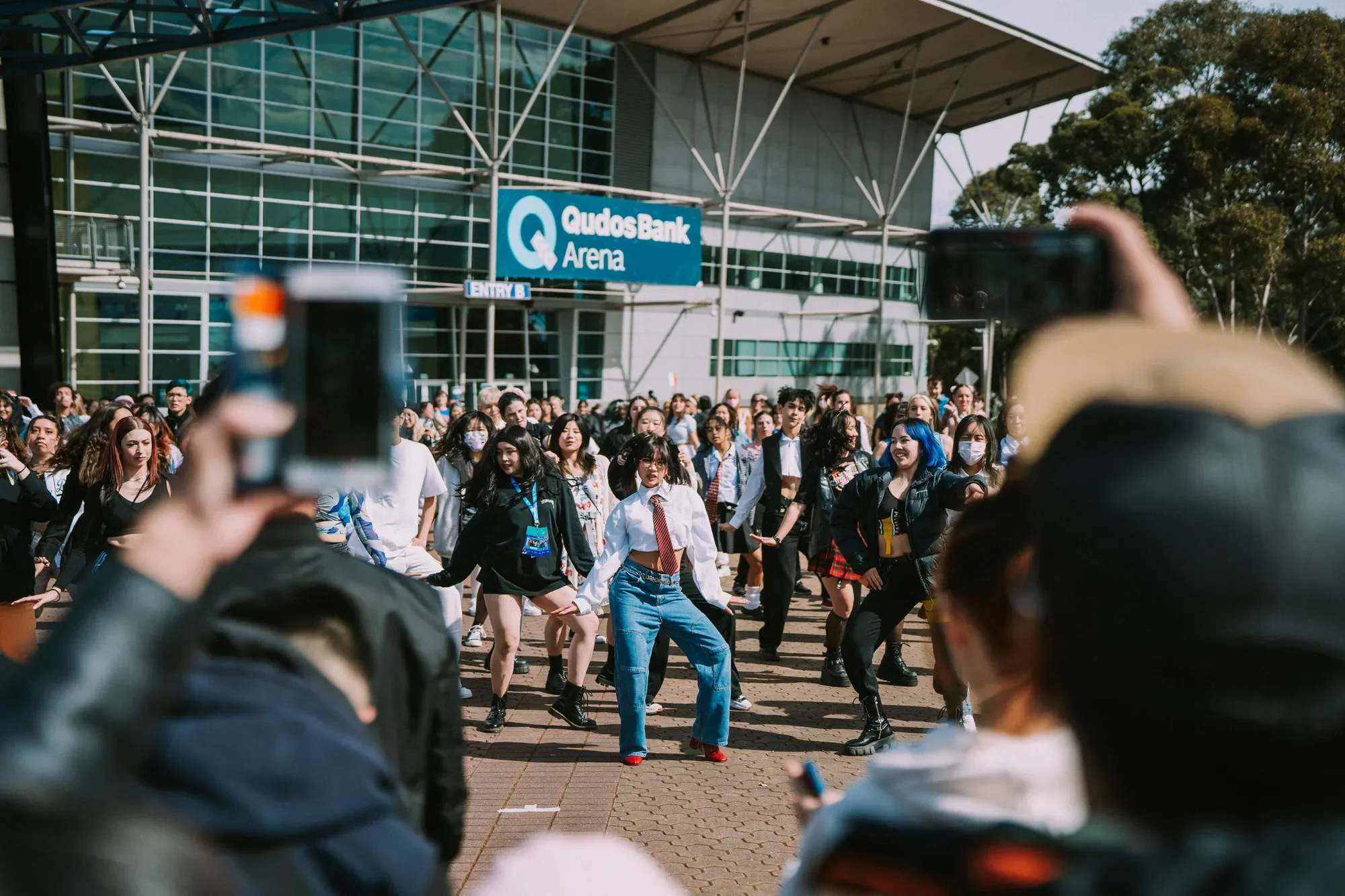 Sydney event photography: Choreographed dance flash mob outside Qudos Bank Arena with a crowd watching.